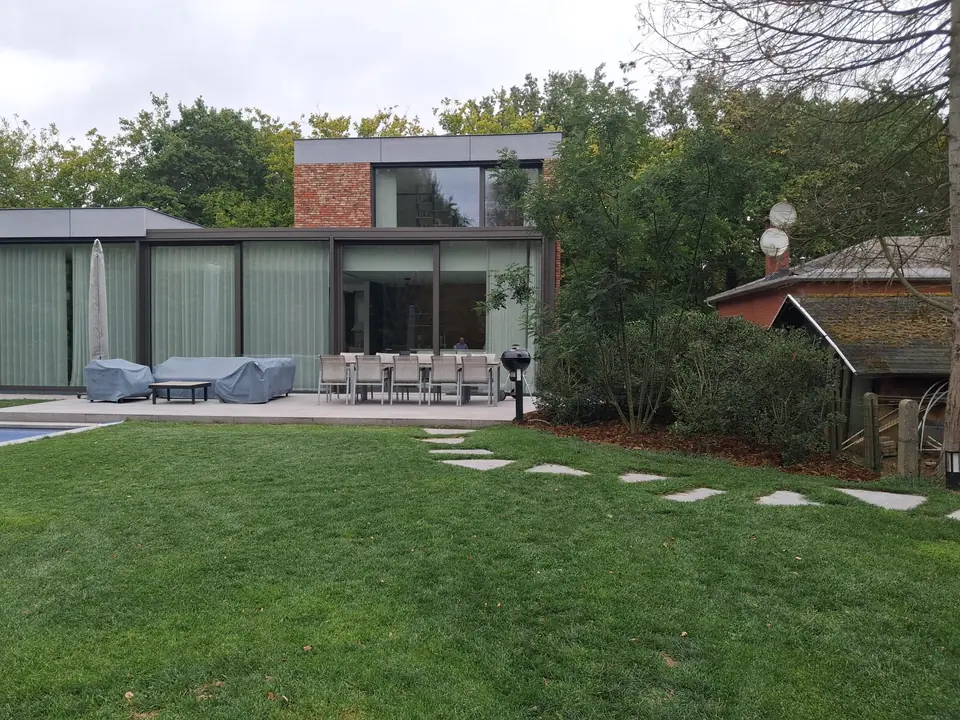 Tuin met gazon en stapstenen bij een moderne woning